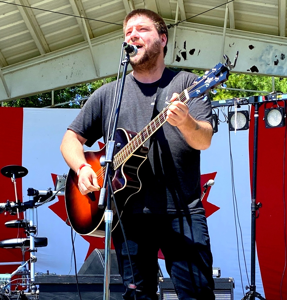 Josh Dimmel on stage with canada flag behind him.