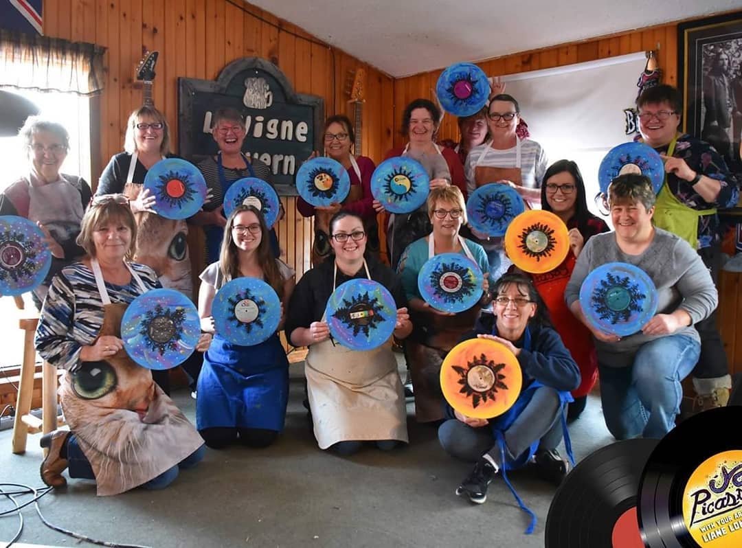 Paint social at Lavigne Tavern. Ladies holding vinyl records painted with blues, orange and yellow.